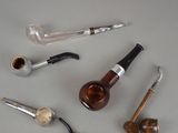 a lot of different types of smoking pipes on the table
