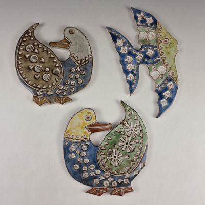 three decorative birds are sitting next to each other on a white surface