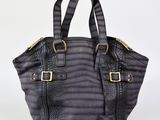 Le petit sac fourre-tout est noir et comporte une boucle dorée.