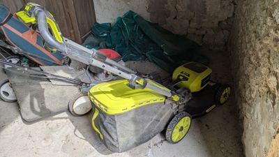 une tondeuse à gazon posée par terre à côté d'un sac