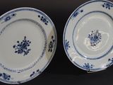 two blue and white plates with flowers on them sitting on a table