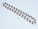 a close up of a white and black beaded necklace on a white surface