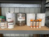 several buckets of paint are sitting on a shelf in a garage