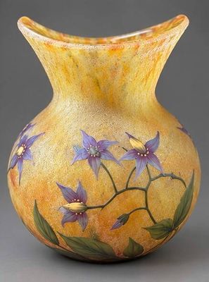 un vase jaune sur lequel sont peintes des fleurs violettes