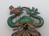 a green and gold brooch with a dragon on it
