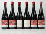 six bottles of red wine are lined up on a table