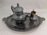 a silver tea pot and a silver cup on a tray
