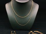 un ensemble composé d'un collier et d'un bracelet en or, posé sur un présentoir pour mannequin