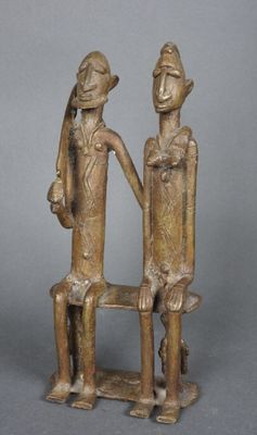 deux figurines en bronze représentant deux personnes assises sur un banc