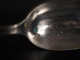 a silver spoon with a tiny blue dot on it