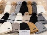 des bonnets tricotés avec des pompons, posés sur un lit
