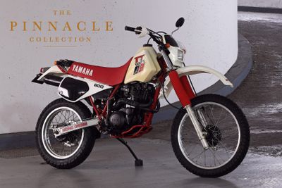 a red and white motorcycle parked in front of the pinnacle collection sign