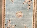 une photo d'un tapis bleu et beige orné de fleurs