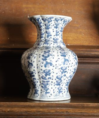 a blue and white vase sitting on a wooden shelf