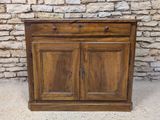 une armoire en bois à deux portes, avec un tiroir en dessous