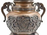 a bronze urn with a cat on top of it