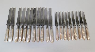 huit couteaux en métal argenté et six couteaux sont alignés sur une surface blanche