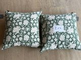 deux coussins verts et blancs ornés de fleurs blanches