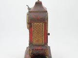 a small red and gold clock on a white surface