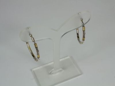 pair of gold and silver hoop earrings on a clear display stand