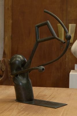 une statue représentant un homme tenant un objet circulaire posé sur une table