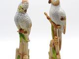 deux figurines d'oiseaux perchées sur une souche d'arbre