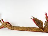un bateau-dragon doré à la queue rouge sur un fond blanc