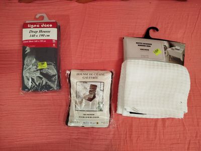trois objets posés sur un lit recouvert d'une couverture rose