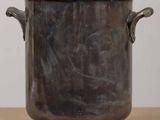 a large metal pot sitting on a wooden table