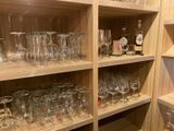 bottles and glasses are lined up on the shelves of a wine cellar