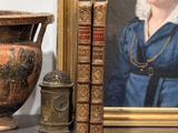 une photo d'une femme en robe bleue, à côté d'un vase et de livres