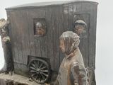 a statue of a man and a woman standing in front of a horse drawn carriage