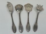 four silver spoons are lined up in a row on a white surface
