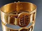 a close up of a gold bracelet with a buckle on it