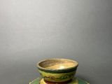 a small green and yellow bowl on a saucer