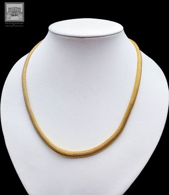 a gold necklace on a white mannequin with a black background