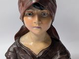 statue of a woman wearing a brown hat and a brown jacket