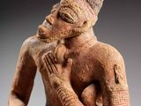a close up of a statue of a man sitting on a rock