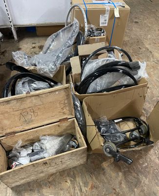 Plusieurs cartons contenant du matériel électrique de toutes sortes sont posés par terre.