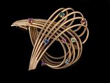 un gros plan sur une broche en or sertie de pierres multicolores