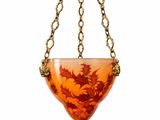 an orange glass hanging planter with a dragon design on it