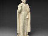 une statue en marbre blanc représentant une femme tenant une cloche