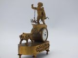 a gold clock with a statue of a man and a dog on it