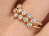 un gros plan de la main d'une personne tenant une bague en or sertie de trois diamants