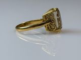 a gold ring with a stone in it on a white surface