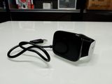 un petit appareil noir branché à un chargeur posé sur une table