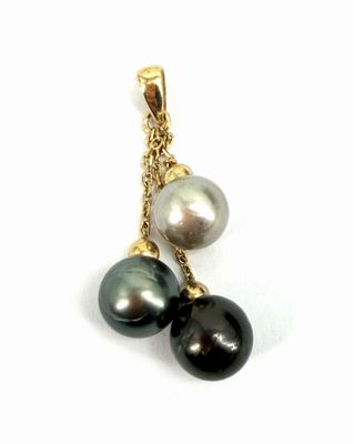 un gros plan d'un pendentif en perle noire et blanche monté sur une chaîne en or
