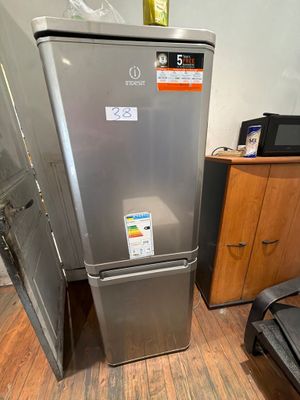 a silver refrigerator in the corner of a room with a black chair