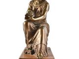 a bronze statue of a woman sitting on a wooden base