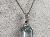 an aqua blue topaz pendant with a diamond set in the center